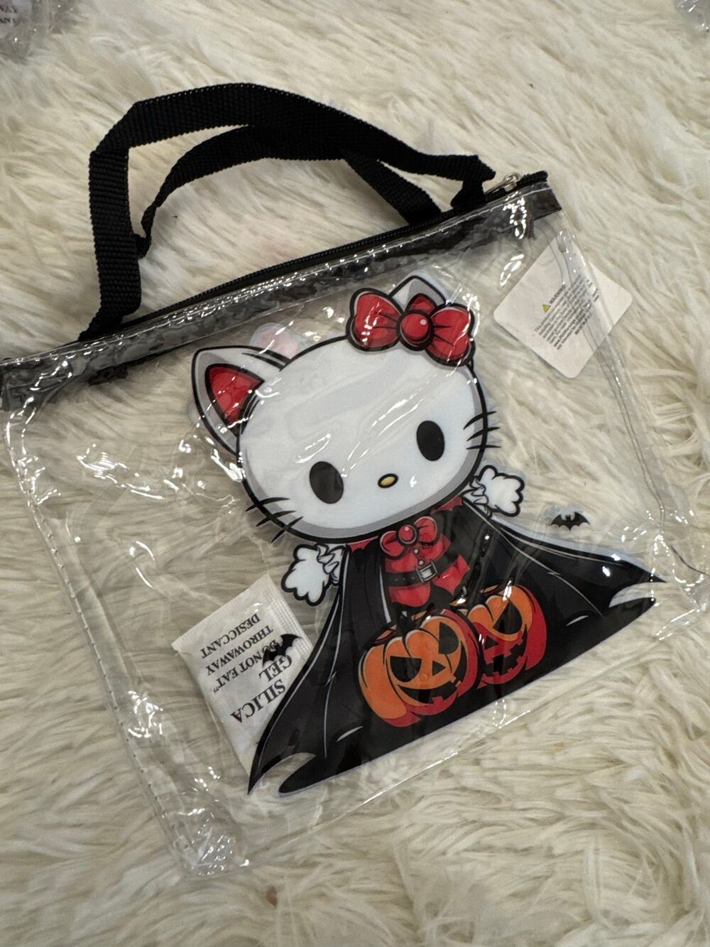 Hello Kitty Halloween clear bag in a black cape holding jack-o'-lanterns